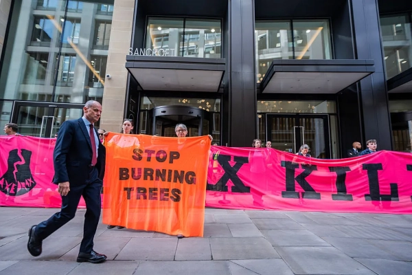 Изображение может содержать одежду Джоанны Кацор, обувь, аксессуары для обуви, официальную одежду, галстук, взрослого человека, идущего и баннер