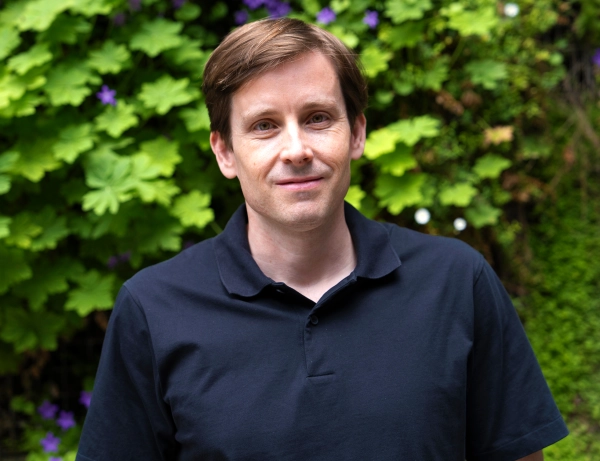 Новое доказательство «супердиффузии» исследует таинственную математику турбулентности 2 Мужчина улыбается перед доской.