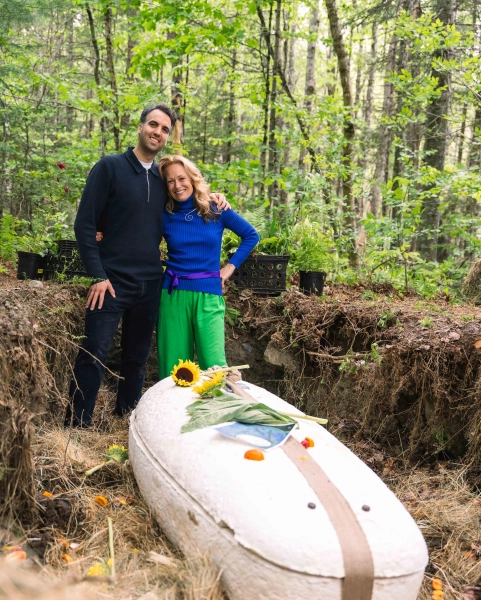 Грибной гроб стал первым примером «зеленых похорон» в США. 2 Мужчина и женщина стоят бок о бок, обнявшись, в лесу. Они стоят в канаве рядом с гробом для грибов, на котором лежат подсолнухи.