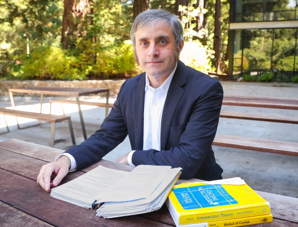 Мужчина читает газеты за столиком на открытом воздухе.