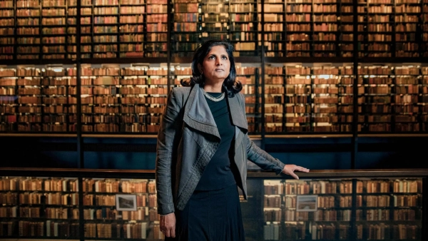 Одна «голая» чёрная дыра переписывает историю Вселенной 5 Женщина стоит в библиотеке перед стеной книг.