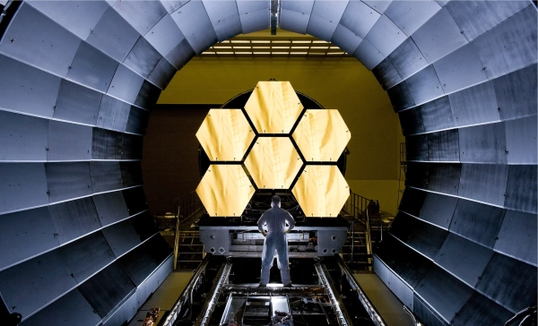 Одна «голая» чёрная дыра переписывает историю Вселенной 2 Шесть золотых сотовых зеркал возвышаются над человеком в чистом костюме.