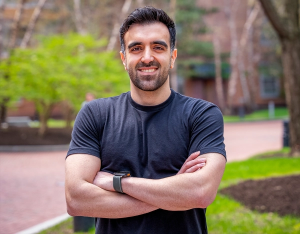 Сохейл Бехнежад в черной футболке стоит на фоне коричневых деревьев.