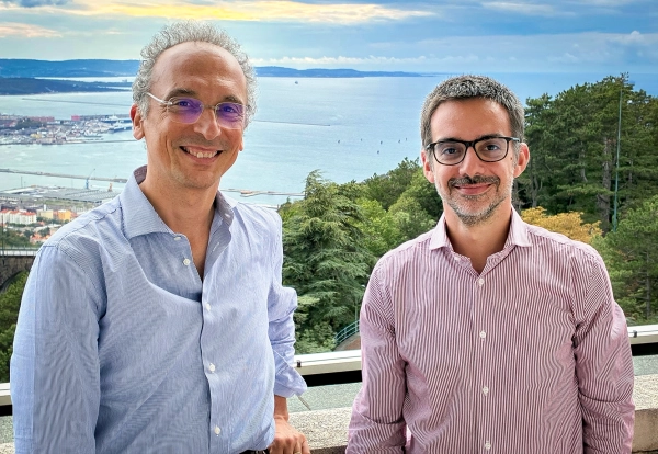 Скрытая математика океанских волн становится видна 2 Двое мужчин, один в синей рубашке, другой в красной, стоят на фоне вида на Триестский залив.