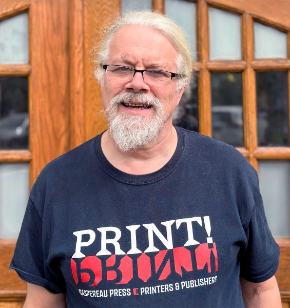 Мужчина в футболке стоит снаружи.