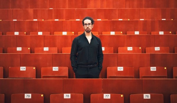 Мужчина в черном стоит в зрительном зале.