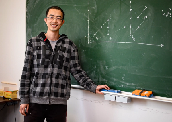 Мужчина у доски, покрытой рисунками из точек и линий.