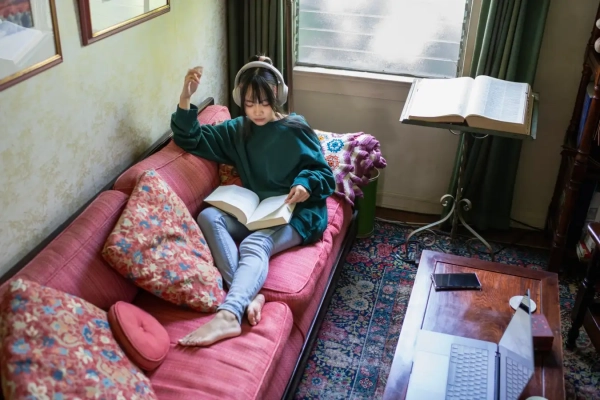 Ваш мозг переживает четыре драматических периода изменений в возрасте от 0 до 90 лет 3 Молодая женщина читает книгу в наушниках.