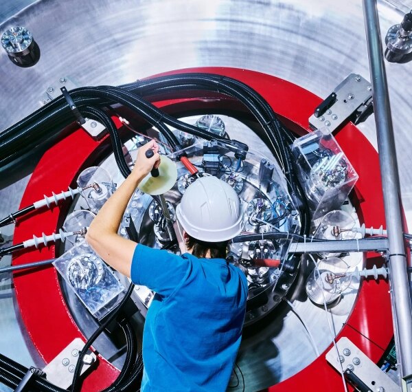 Инженер в каске работает с высокотехнологичным оборудованием в лаборатории.