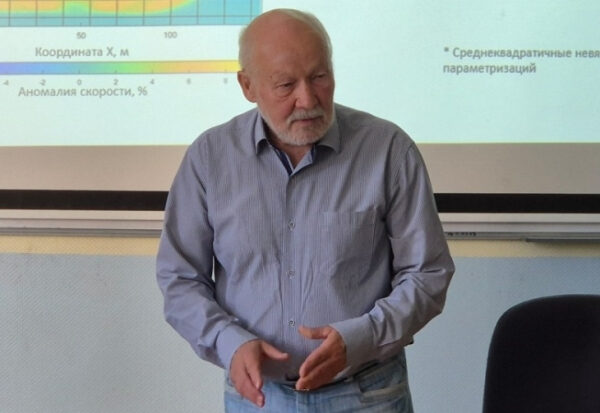 Пожилой мужчина проводит презентацию в классе около проектора.