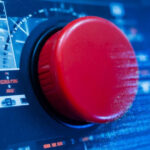 Красная кнопка на панели управления в технологическом окружении.