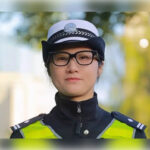 Полицейский в форме с фуражкой и светоотражающим жилетом на улице.