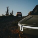 Два внедорожника на холме на закате в горах.