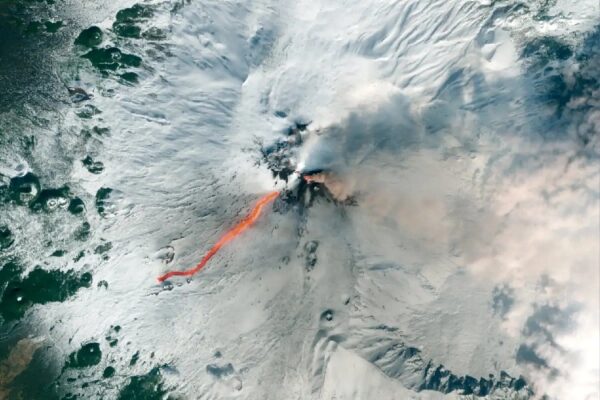 Спутниковый снимок извержения вулкана: поток раскалённой лавы на заснеженном склоне.