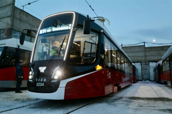 Современный трамвай на улице зимой, вечернее освещение, городской транспорт.
