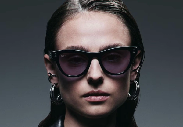 Женщина в солнцезащитных очках и серьгах-кольцах на темном фоне.