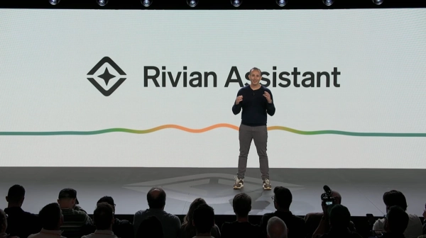 Человек на сцене презентует Rivian Assistant перед аудиторией.