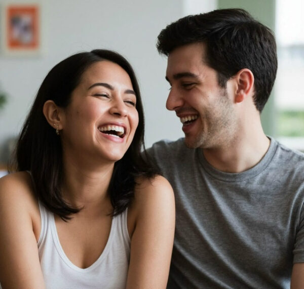 Пара смеётся и смотрит друг на друга в уютной домашней обстановке.