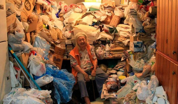 Комната, заполненная множеством хлама и упаковок, на фоне деревянного шкафа.