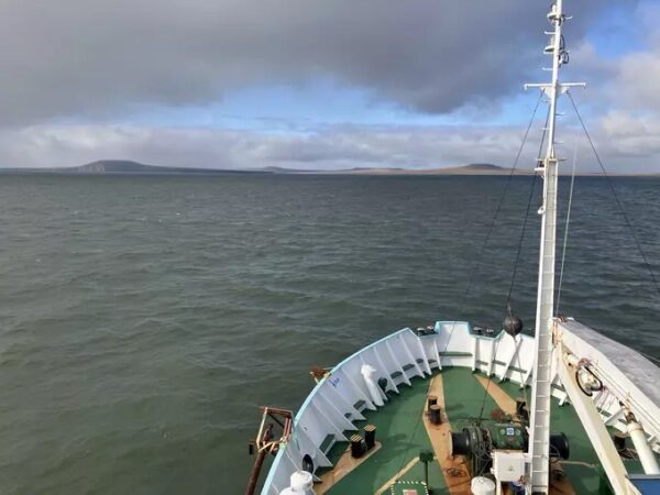 Палуба корабля на фоне спокойного моря и облачного неба, видны далекие острова.