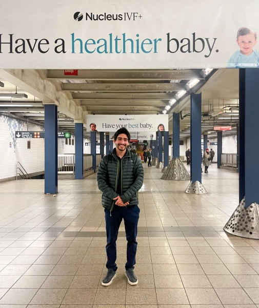 Садеги позирует под первой рекламой в ряду. Надпись над ним гласит: «Nucleus IVF+: родите более здорового ребёнка». Слово «более здоровое» подчеркнуто.