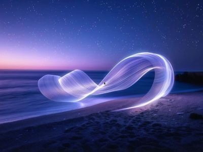 Световая абстракция над морем на фоне звездного неба ночью.