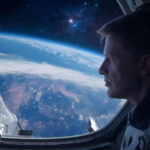 Вид на Землю из космоса через иллюминатор корабля, звезды на фоне.