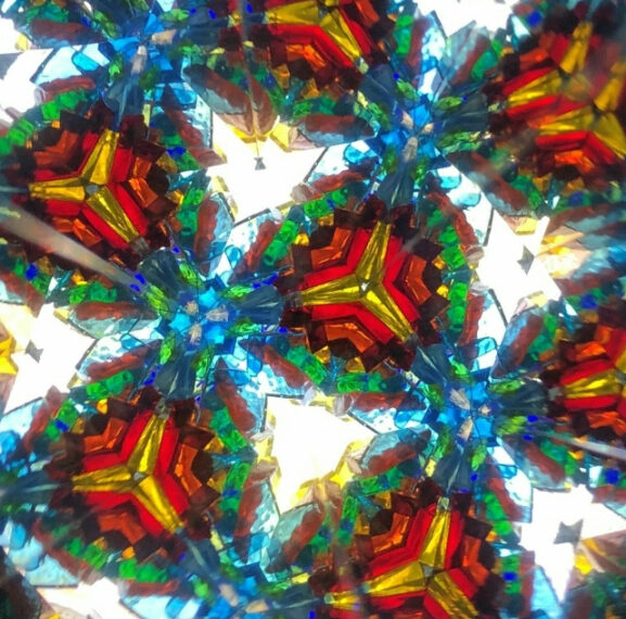 Абстрактный узор калейдоскопа с яркими цветами: красным, синим, зелёным и жёлтым.