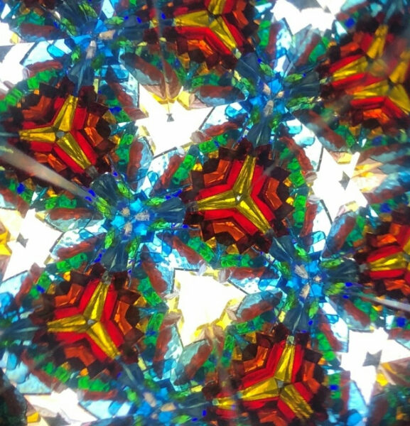 Абстрактный узор калейдоскопа с яркими цветами: красным, синим, зелёным и жёлтым.