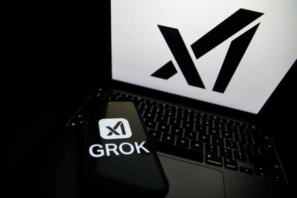 Логотип X AI на экране ноутбука и смартфона с надписью GROK на фоне.