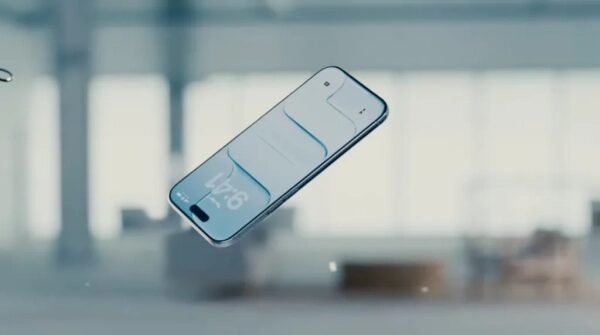 Смартфон в воздухе на фоне размытого помещения с большими окнами.