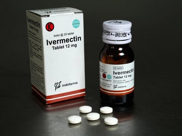 Упаковка и пузырек препарата ивермектин 12 мг с четырьмя таблетками на столе.