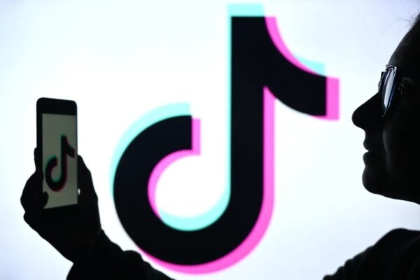 Силуэты с логотипом TikTok на экране и телефоне, крупный план.