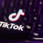 Логотип TikTok на фоне клавиатуры с фиолетовой подсветкой.