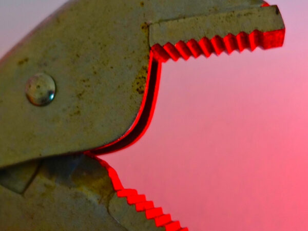 Крупный план металлического зажима с красной подсветкой на фоне.
