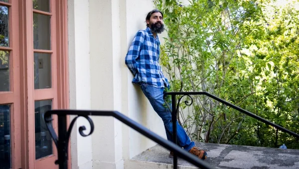 Ману Пракаш прислонился к зданию на территории кампуса Стэнфордского университета.