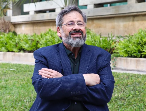 Бородатый мужчина в очках и темно-синем костюме.