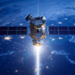 Спутник в космосе над Землей с ночной подсветкой и лучом света вниз.