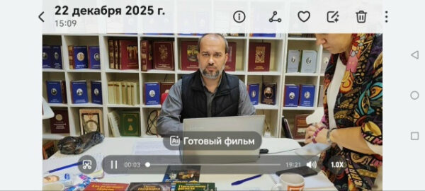 Человек за ноутбуком в библиотеке с книгами на полках, декабрь 2025.