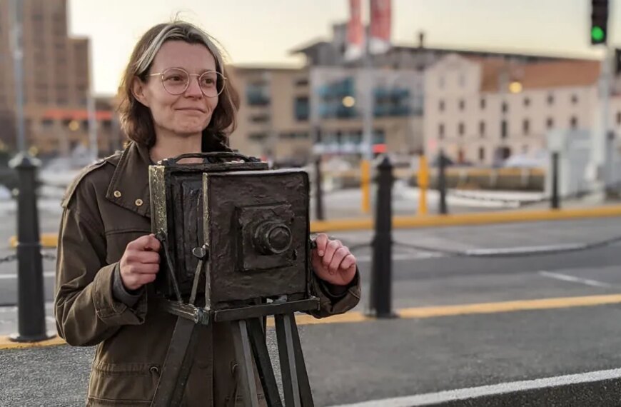 Женщина с ретро-камерой на улице города.