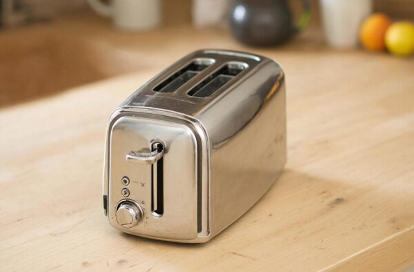 Металлический тостер на кухонном столе с двумя отделениями для хлеба.