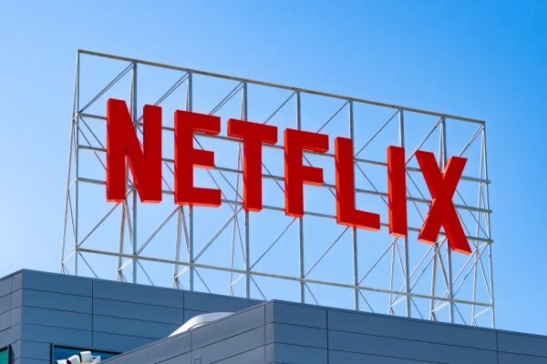 Логотип Netflix на крыше здания на фоне синего неба.