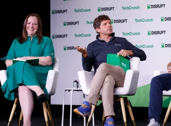 Участники на конференции TechCrunch Disrupt сидят на сцене и обсуждают новый проект.
