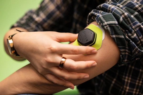 Добро пожаловать в штат, где ведется наблюдение за здоровьем 3 Крупный план человека, закрепляющего биосенсор Nix Hydration на бицепсе с закатанными рукавами.