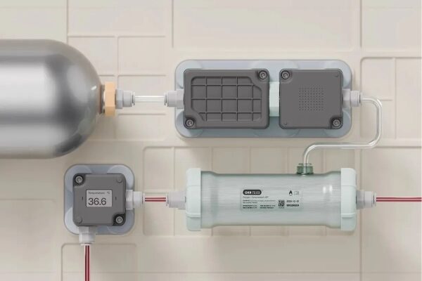 Медицинское оборудование с манометром, трубками и баллоном на фоне плиточной стены.