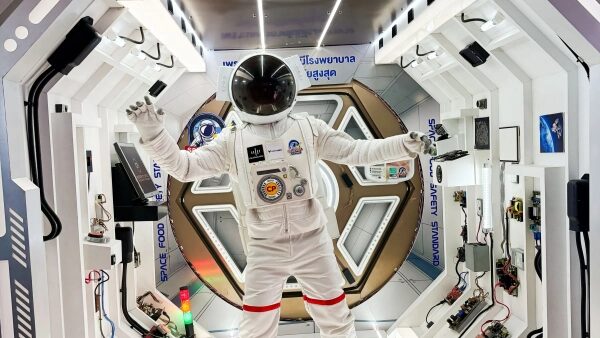 Астронавт в белом скафандре внутри космического модуля.