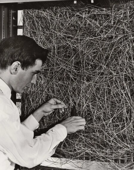 Мужчина работает с множеством запутанных проводов в компьютерной системе.