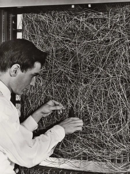 Восхождение ИИ-терапевта 2 Мужчина работает с множеством запутанных проводов в компьютерной системе.