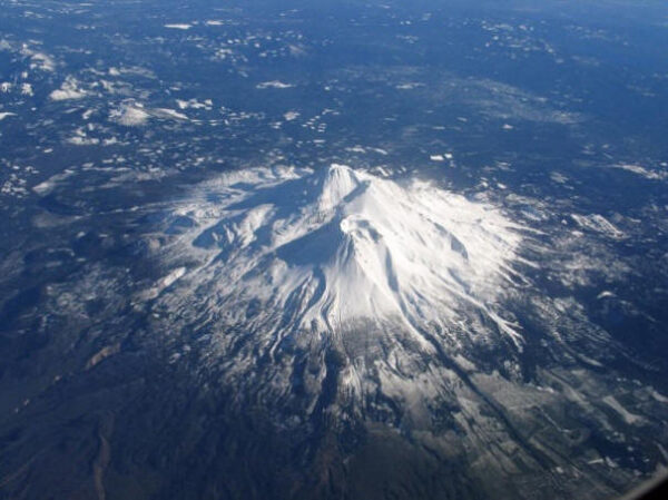 Гора покрытая снегом на фоне лесного ландшафта, вид сверху.