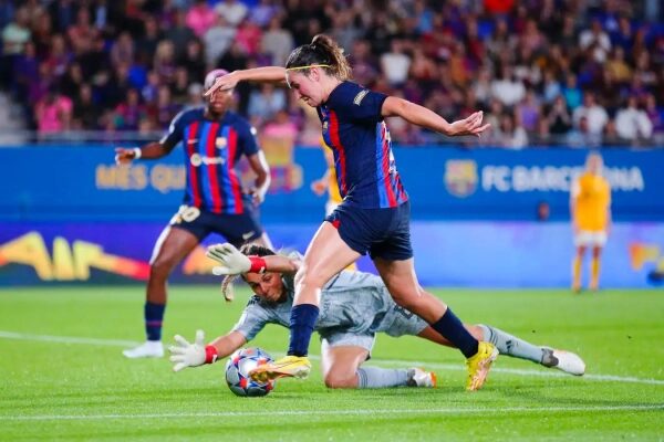 Футболистка обходит вратаря на матче, спортивное действие на поле.